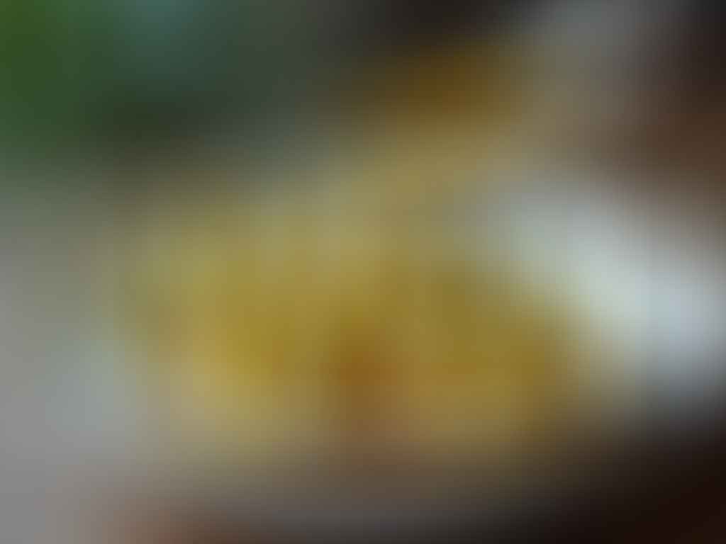 Poires à botzi nappées d’une sauce dorée, servies dans une assiette blanche sur un fond rustique en bois.