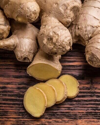1 Gingembre coupé en tranches fines sur fond de bois foncé, racines fraîches et texture naturelle
