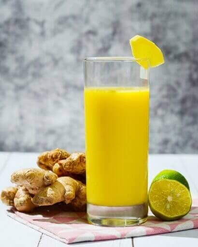 2 Gingembre frais avec jus détox aux agrumes, servi avec citron vert sur serviette rose