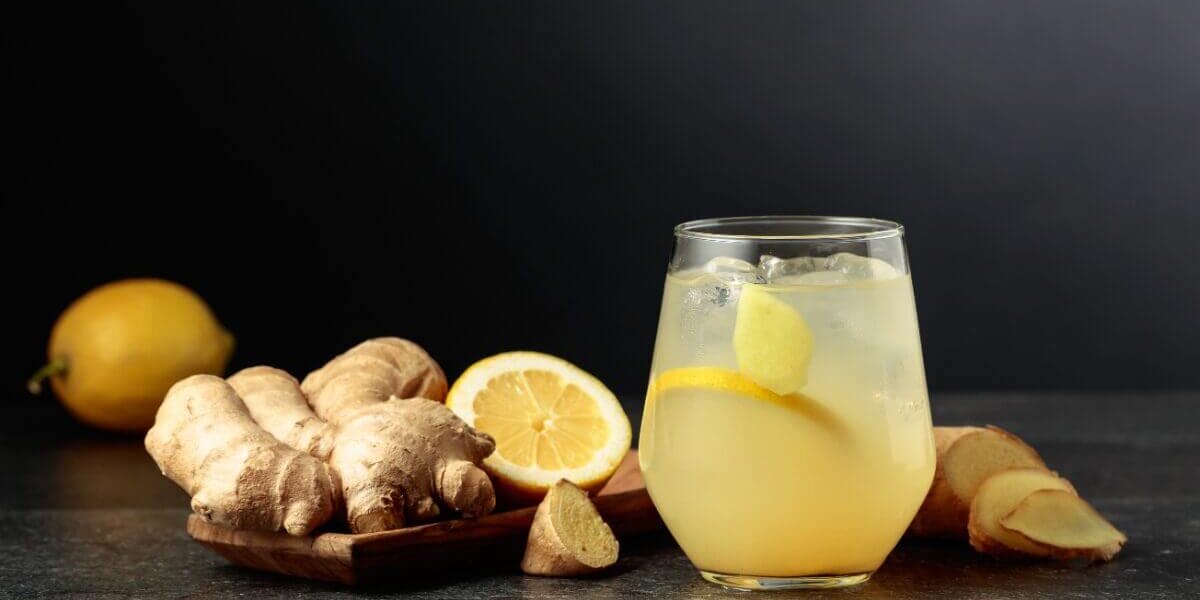 Gingembre Gingembre frais et citrons sur planche en bois avec boisson rafraîchissante au citron et glaçons