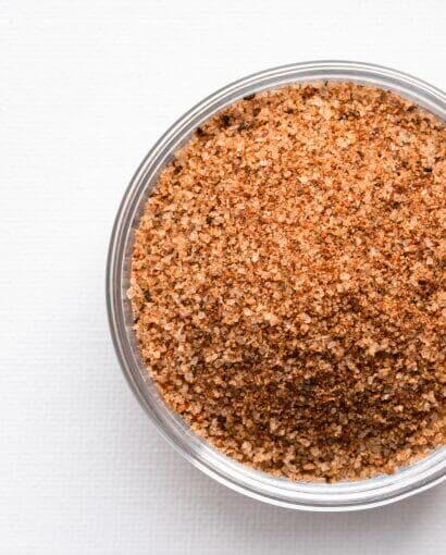 Mélange Cajun en poudre finement moulu présenté dans un bol en verre transparent sur fond blanc épuré