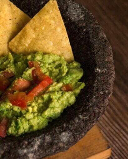 mélange guacamole 6 Mélange guacamole crémeux servi dans un mortier volcanique noir avec chips de maïs dorées
