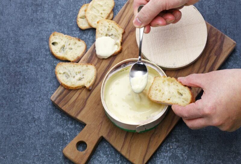 Vacherin Mont d'Or au Four, rôti dans sa boîte, avec pommes de terre et herbes, prêt à être dégusté.