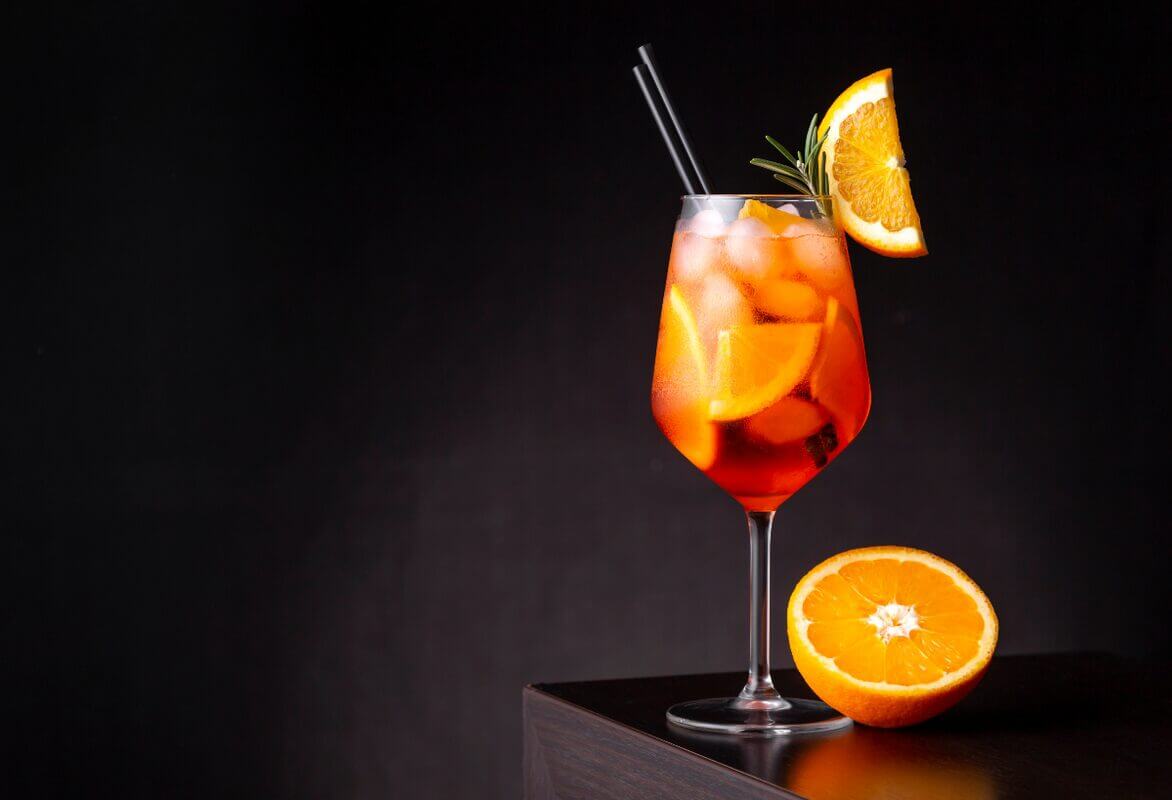 Spritz d'Hiver Épicé 7 Verre de Spritz d'Hiver Épicé avec tranche de clémentine et bâton de cannelle