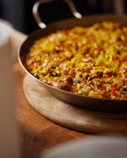 A close-up of a delicious paella dish served on a rustic wooden table, showcasing vibrant ingredients.