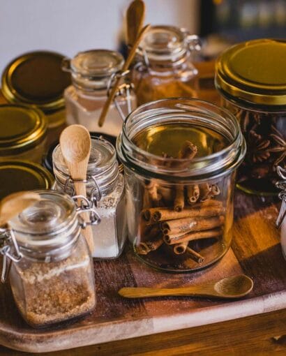 Glass jars filled with spices and kitchen ingredients arranged on a wooden tray.