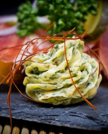 Delicious herb butter and prosciutto on slate, ideal for gourmet food photography.